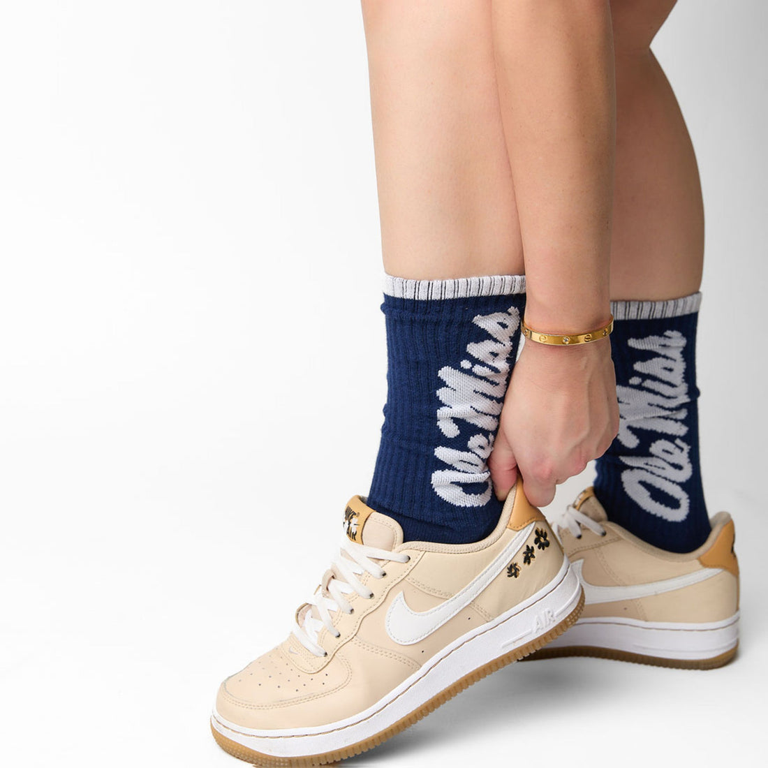 Navy casual crew socks with Ole Miss going up the leg in white worn with cream sneakers by a women.