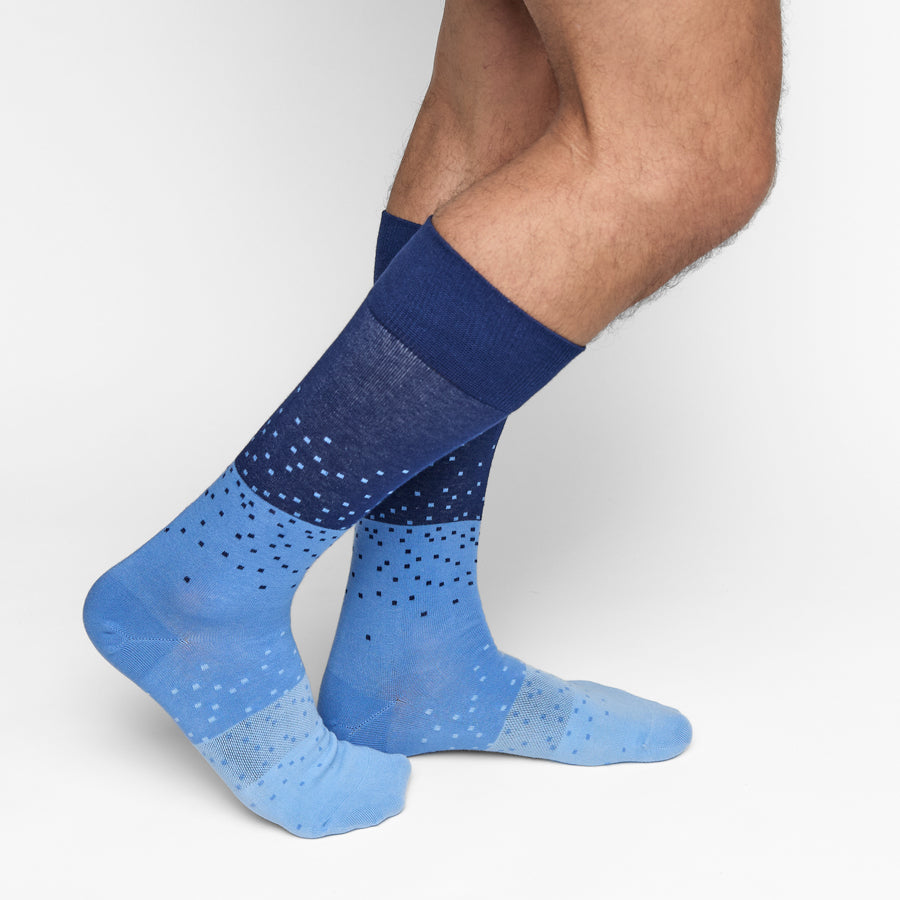 Blue and navy patterned socks worn by a person on a white background