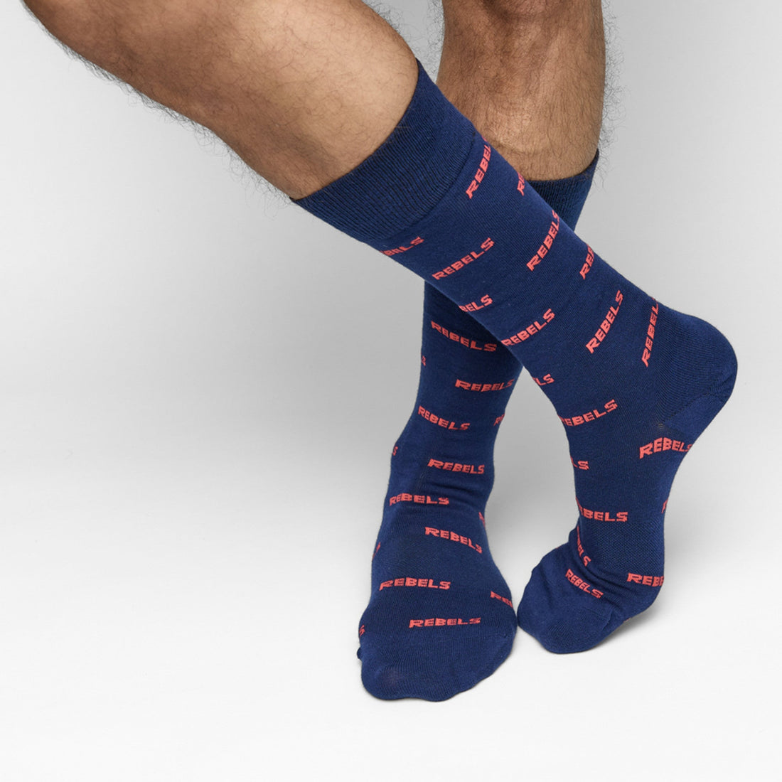Navy dress socks with REBELS in text in an all over pattern on make legs crossed