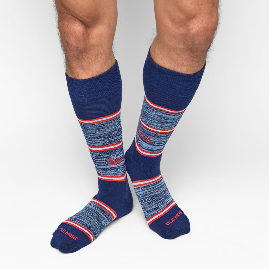 Blue knee-high socks with red and white stripes with Ole Miss on the toe worn by a person on a light gray background