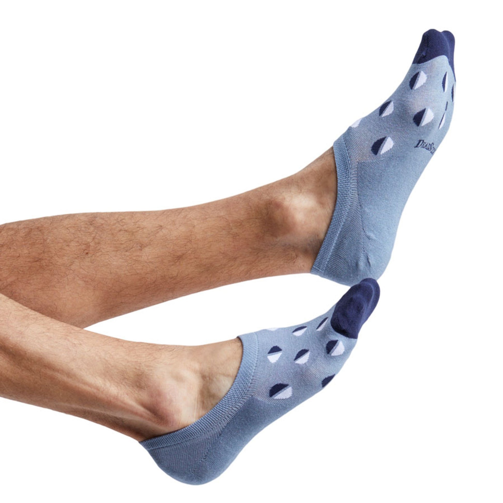 one light blue no show sock with half-circle design of navy and white shown on feet coling into the image from the left