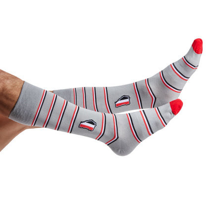 Grey dress socks with red, white, and black mini stripes and the state of georgia in red, black and white on the ankle shown on legs coming into the image from the left