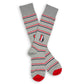 Grey dress socks with red, white, and black mini stripes and the state of georgia in red, black and white on the ankle laid out flat and crossed at the heel.