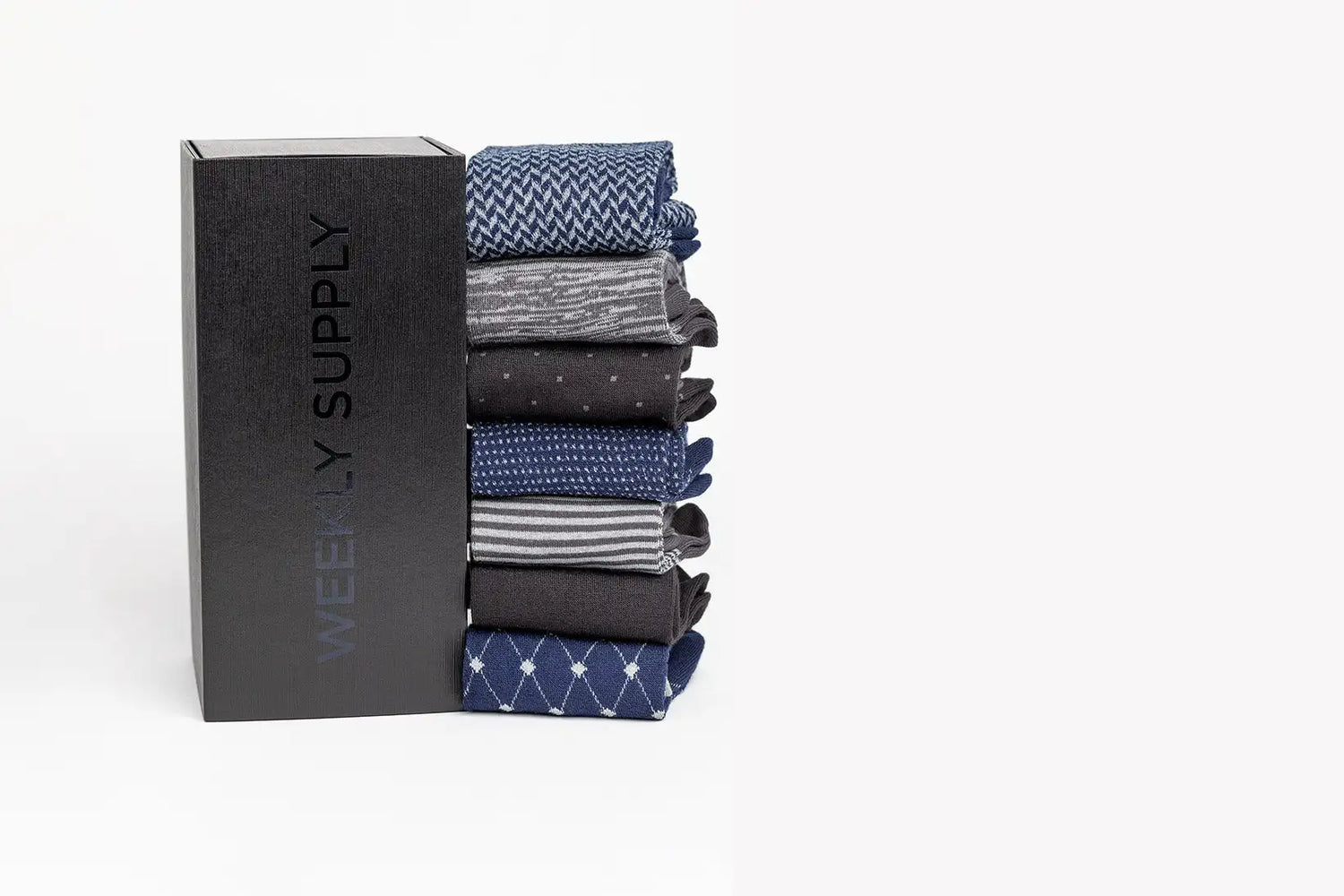 Stack of neatly folded men’s dress socks in various blue, gray, and black patterns with subtle textures.
