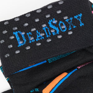 Black dress socks with green, blue, orange and grape accents in a patchwork design close up of TruseStay‚Ñ¢ in the welt.