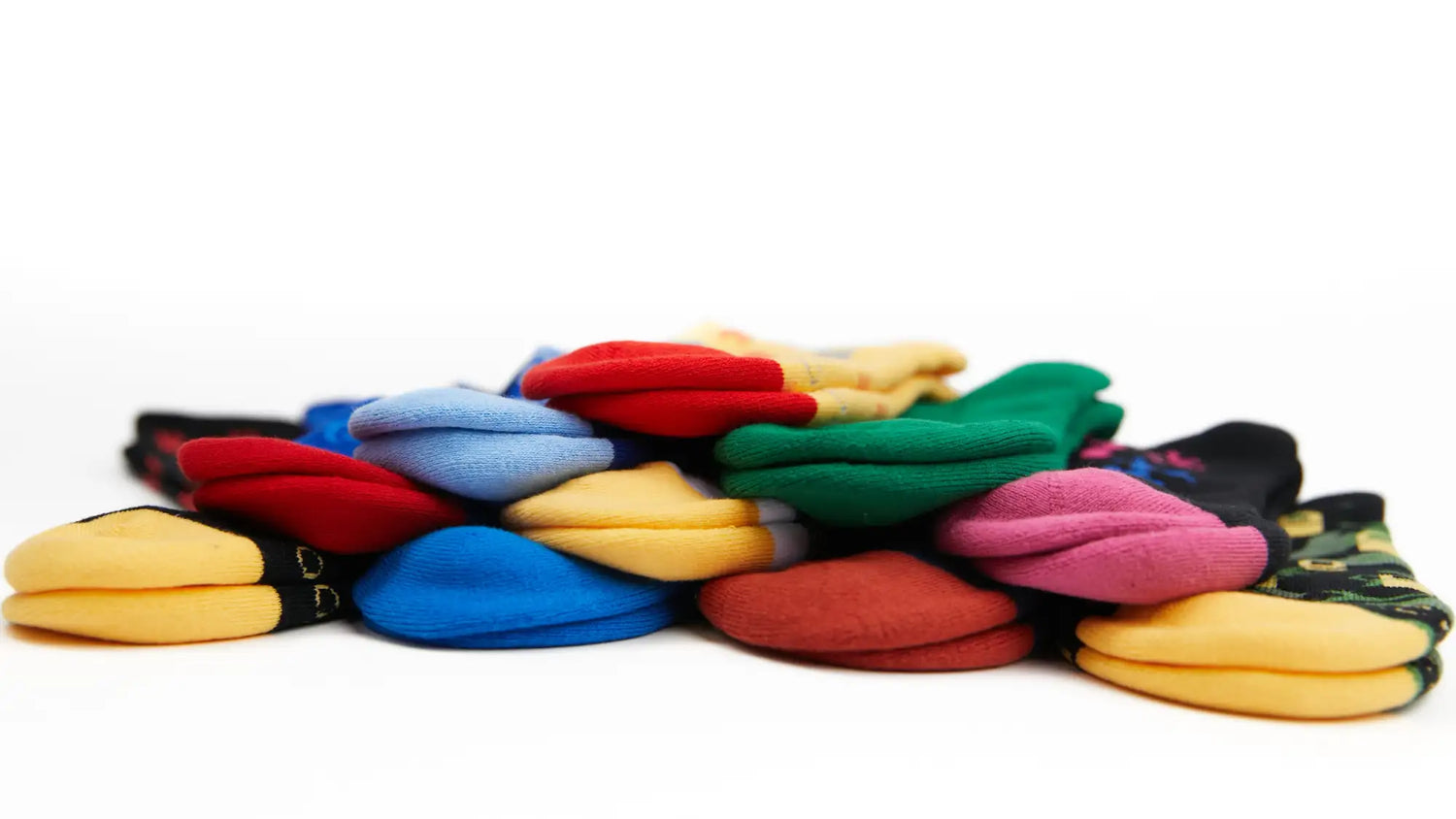 A vibrant pile of assorted colorful socks, featuring solid hues like red, blue, yellow, green and pink.