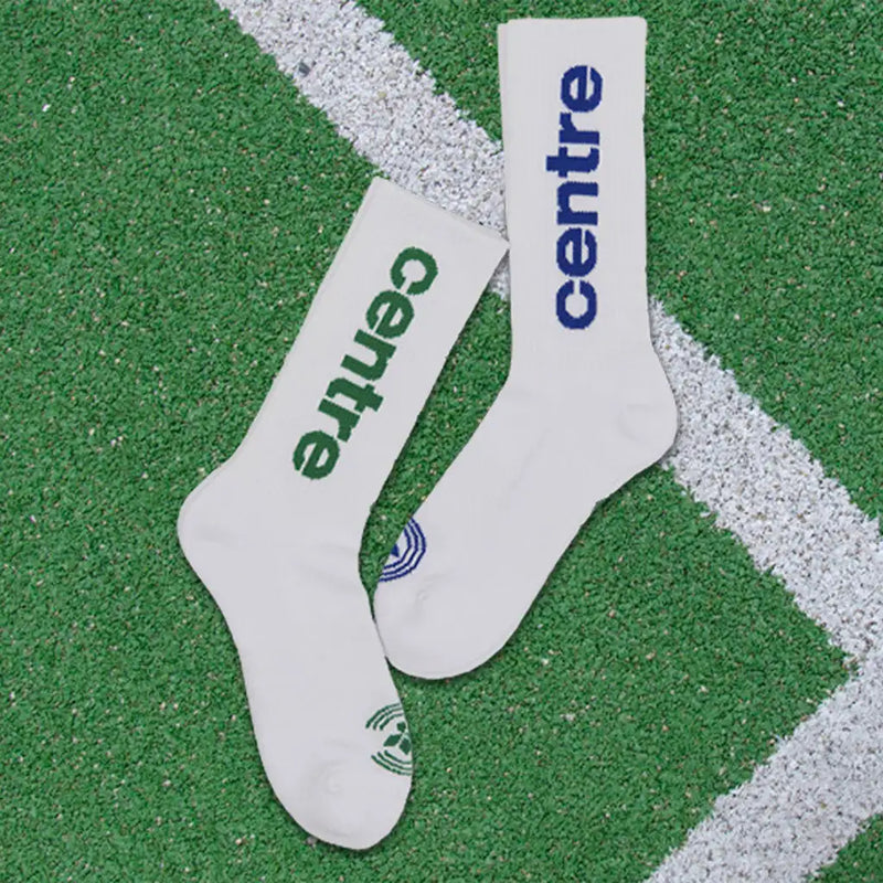 White athletic socks with ’centre’ printed in green and blue lettering, featuring a small logo on the toe.