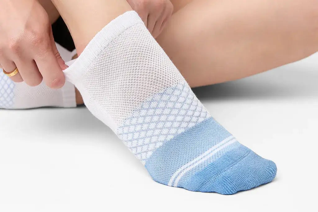 White and light blue athletic sock with a breathable mesh upper, diamond-patterned texture on the footbed, and reinforced toe area.