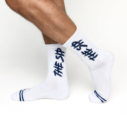 White casual crew socks with THE SIP in navy written down the shown on male model